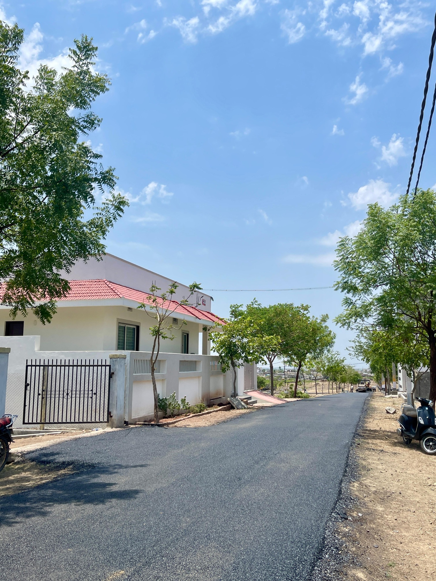 Completed independent house with red-tile roof beside a new black-top road at Sri Krishna Valley